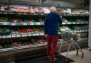 A shopper looking at salad vegetables in a branch of Waitrose