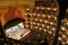 A grand theatre full of people watching an orchestra. Credit: Canva